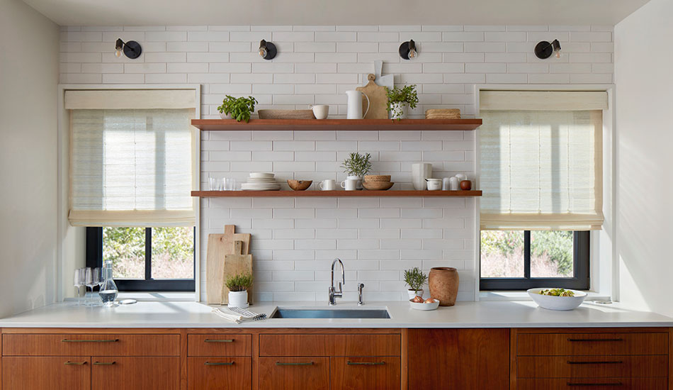 A modern farmhouse kitchen features standard woven shades made of Artisan Weaves Coastline in Muslin for subtle texture