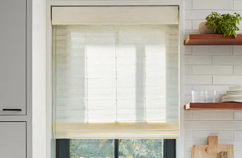 A window in a farmhouse kitchen features a Standard Woven Wood Shade made from Coastline material in Muslin