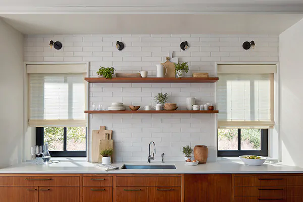 A farmhouse kitchen with wood cabinets features woven window shades made from Coastline material in Muslin
