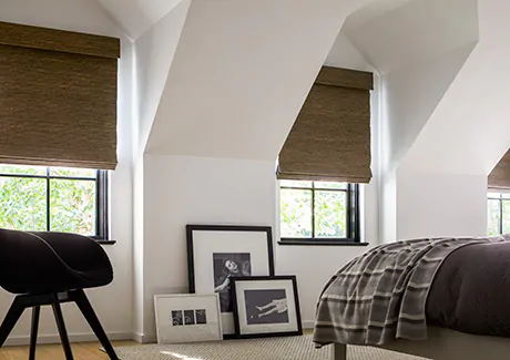 An attic bedroom features privacy shades in the Woven Wood Shade style made of Seaview material and featuring blackout lining
