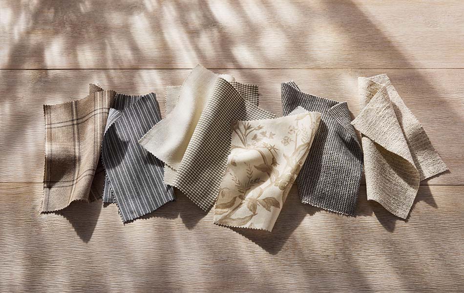 Fabric swatches from the Studio McGee window treatments collections are artistically laid on a wood table