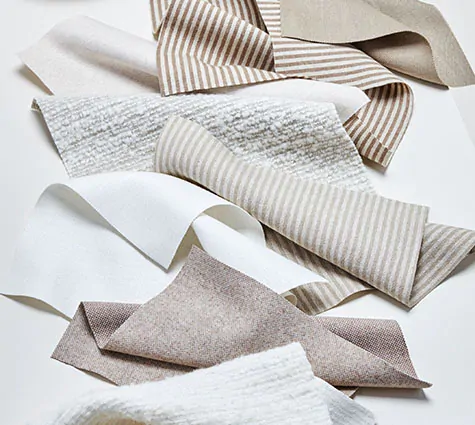 Fabric swatches from the Nate Berkus collection are laid on a white table and can be used for drapes or curtains