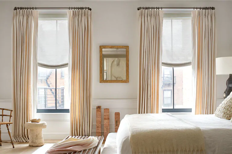 A bedroom has Tailored Pleat Drapery made with Sunbrella Alma in Beige and French return curtain rods Lafayette in Gunmetal