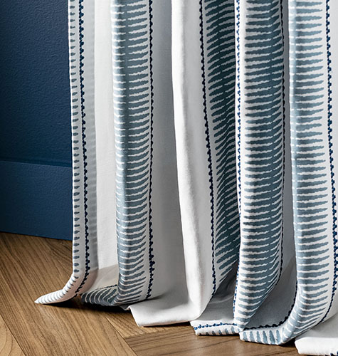 A drape panel made of Alexa Hampton's Baluster in Indigo, showing unique puddle drapes and how long curtains should be for a fuller floor-length look