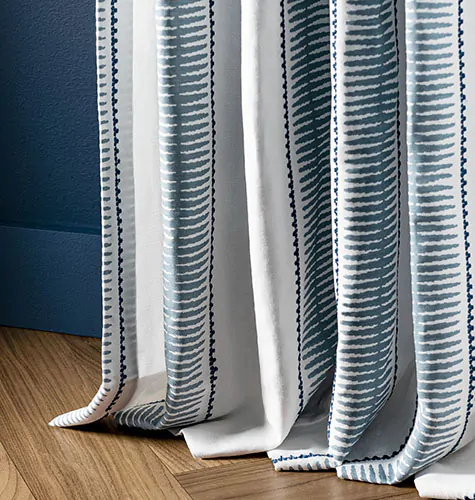 A drape panel made of Alexa Hampton's Baluster in Indigo puddles on the floor in a luxurious, inviting way