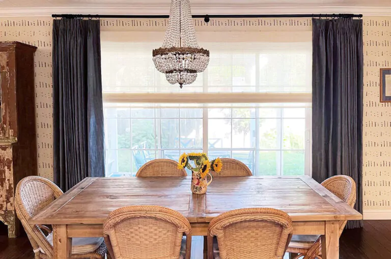A dining room showcases Nathan Turner's window treatment tips by layering Tailored Pleat Drapery and a Woven Wood Shade
