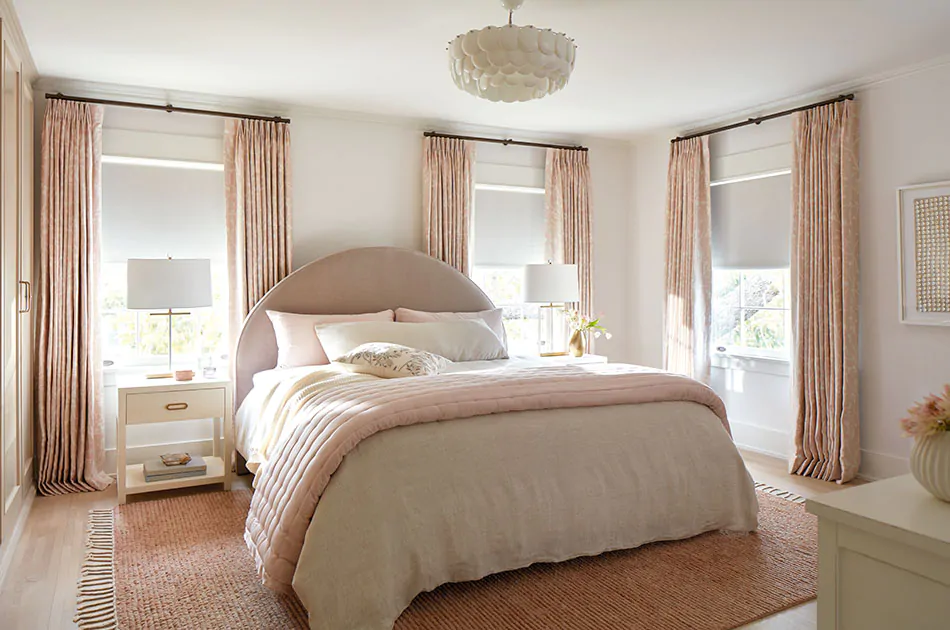 An inviting bedroom features Tailored Pleat Drapery in Chinoiserie Blush with blackout drapery lining for room darkening