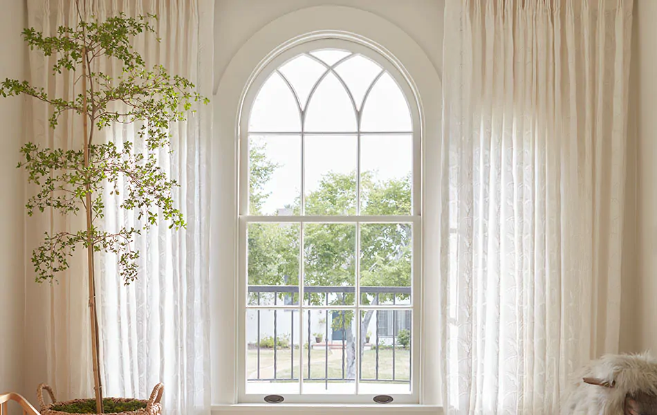 Scandinavian curtains made of Feather Palm Embroidery in Vintage Lace adds a soft, inviting look to a warm white nursery