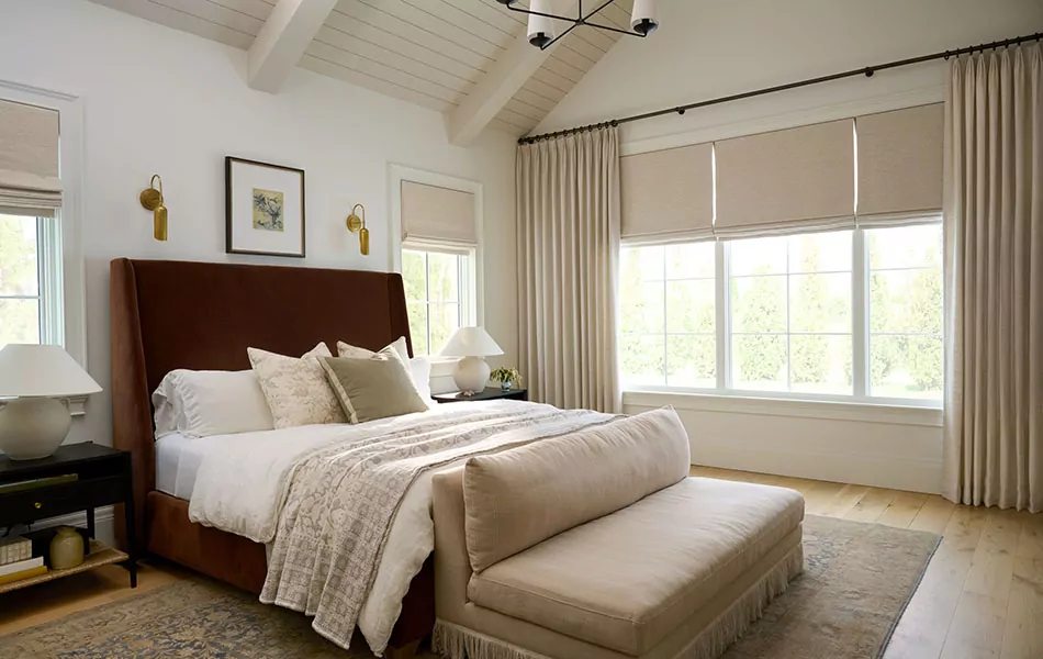 Tailored Pleat Drapery and Flat Roman Shades made of Gypsum Stripe in Canvas hang in a calming bedroom