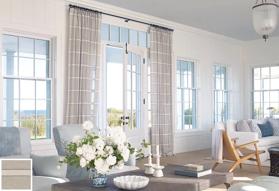 Another example of living room curtain ideas is this bright coastal-inspired space with tailored pleat drapery over the door