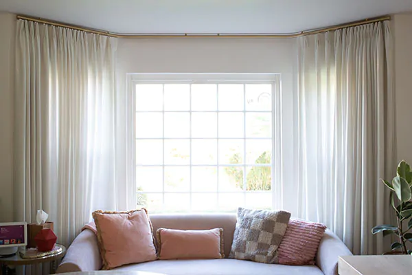 Window treatments for bay windows include Tailored Pleat Drapery made of Heathered Linen in Ivory for a soft, inviting look