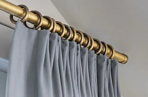 Tailored Pleat Drapery panels made of Andes in Lake hang from rod and rings of Steel Hardware in Antique Bronze