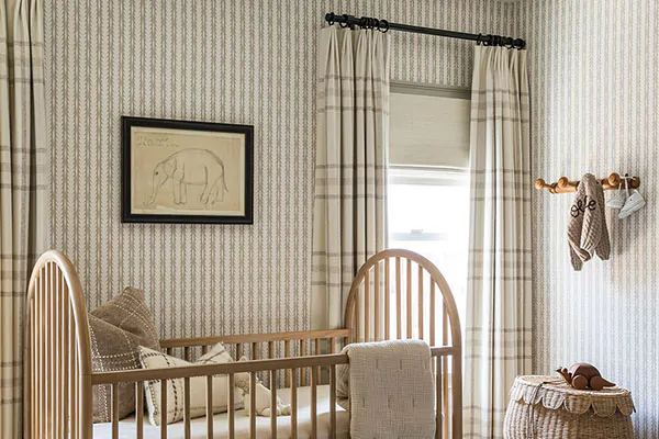 Tailored Pleat Drapery made of Aberdeen in Bisque add a warm, textured look to a cozy nursery with a wooden crib
