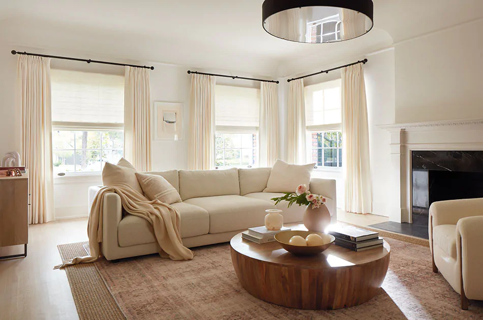 An inviting living room features Tailored Pleat Drapery made of Luxe Linen in Oyster and shows how to install curtain rods