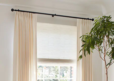 Tailored Pleat Drapery made of Luxe Linen in Oyster is hung outside the window frame on a Madison Track system in Black