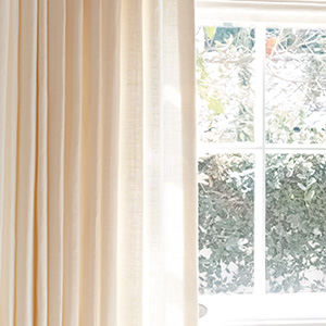 A panel of drapery made of Luxe Linen in Oyster features privacy lining to protect the material and let some light in