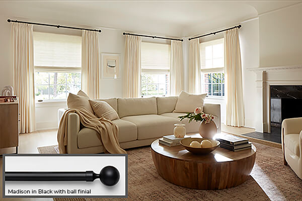 One of the window treatment trends 2024 seen in this living room is high contrast hardware in black with white drapery