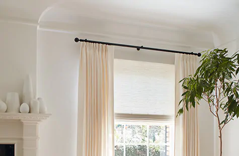 Drapes hung high and wide above a window in a neutral room show how to install drapes to look their best