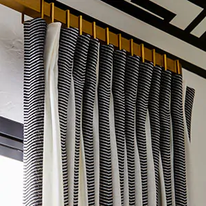 A close up of curtain sheers made of Martyn Lawrence Bullard's Nomad Stripe in Graphite shows a bold striped pattern