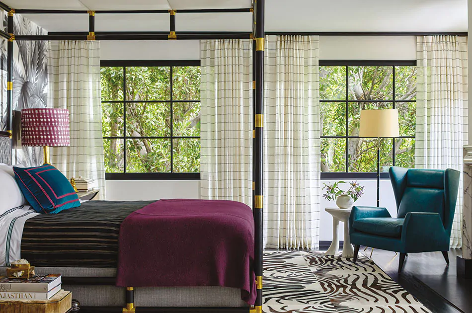 A tropical bedroom with lush colors and greenery features boho curtains made of Sahara Stripe in Onyx