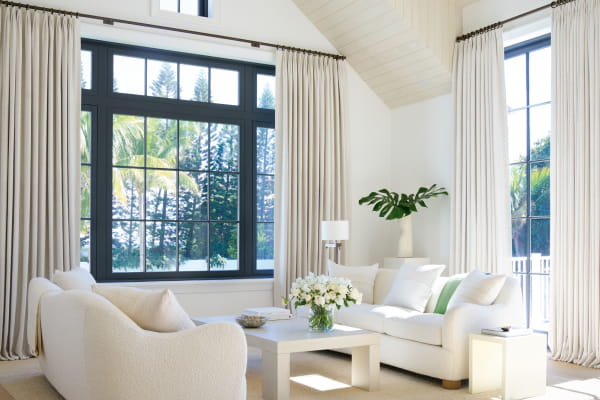 A brightly lit corner with windows featuring Petal Tailored Pleat Drapery in Pearl from the Victoria Hagan collection.