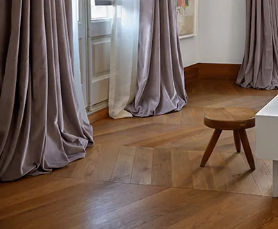 Lush boho curtains made of Tailored Pleat Drapery in Posh Velvet and Lannister Sheer puddle on chevron hardwood floors