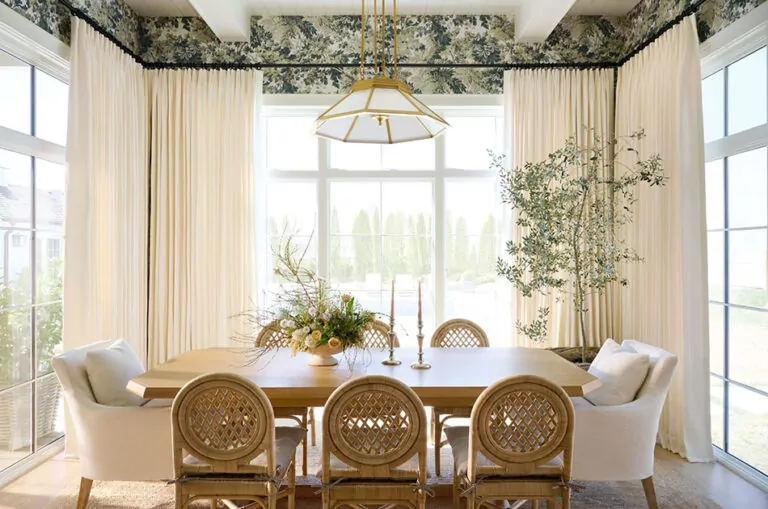 A dining room with windows on all sides has Studio McGee window treatments made of drapery in Stonewash, White