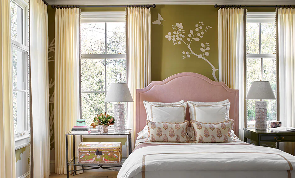 A warm inviting bedroom features olive green walls and curtain sheers made of Sunbrella Vitela in Ivory