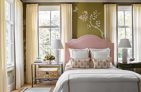 Boho curtains made of Tailored Pleat Drapery of Vitela in Ivory offer a warm tone to the olive green walls of a bedroom