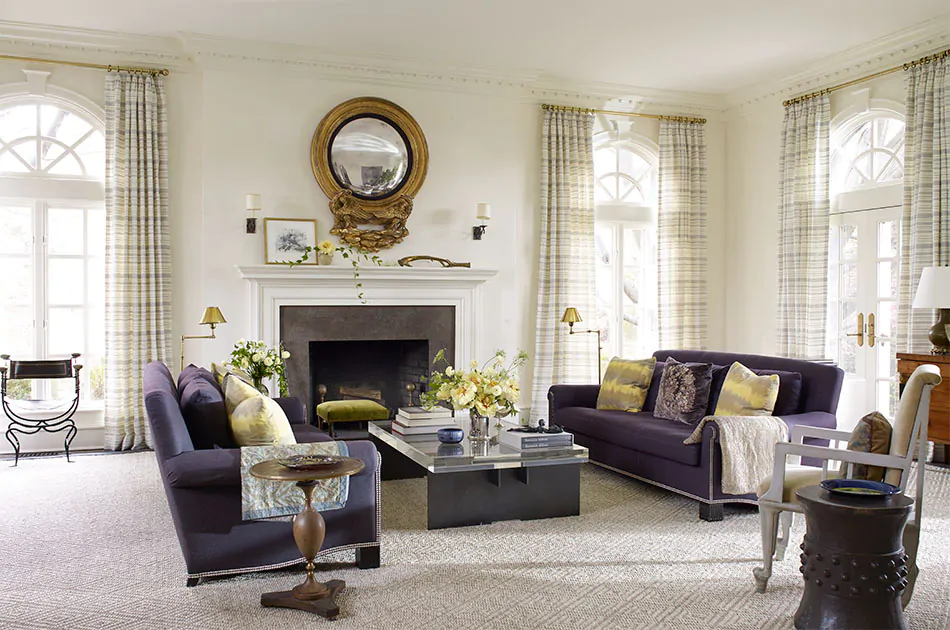 An elegant living room features curtains for arched windows made of Tailored Pleat Drapery in Tidal Line, Slate