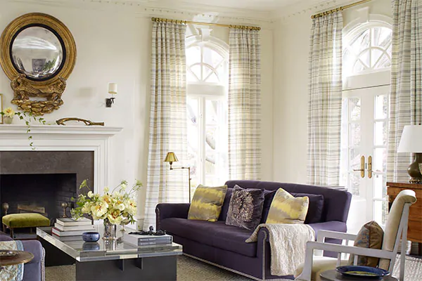 An elegant, luxe living room features curtains for arched windows made of Tailored Pleat Drapery in Tidal Line, Slate