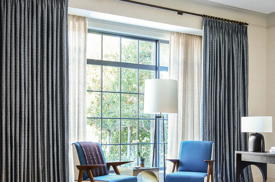 A sitting area with a deep window features layered curtains one of Breezy in Sand and one of Vanda in Midnight on two rods