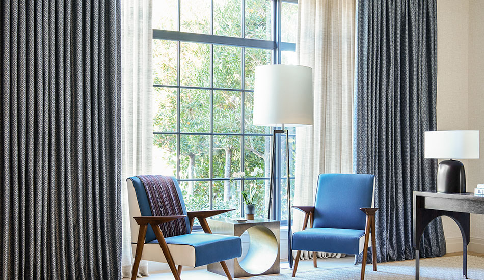 Two layers of Tailored Pleat Drapery made of Breeze in Sand and Vanda in Midnight adorn a large window in a sitting area as layered window treatments for privacy and light control