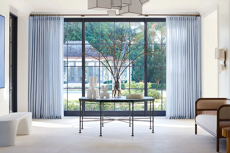A reception hall has window treatments for large windows made of Tailored Pleat Drapery in Casa Stripe, Sky