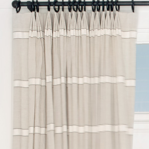 A close up of Tailored Pleat Drapery made of Harbor Stripe in Sand shows the three-finder pleat and east-west stripe design