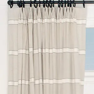 A close up of Tailored Pleat Drapery made of Harbor Stripe in Sand shows the three-finder pleat and east-west stripe design