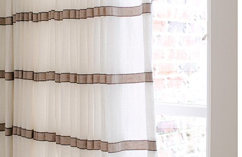 A close up of curtain sheers made of Victoria Hagan's Harbor Stripe in Stone shows how the light filters through a pattern