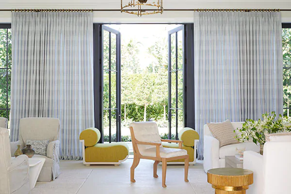 Tailored Pleat Drapery made of Jasmine in Sky are used as sunroom window treatments in a large conservatory space