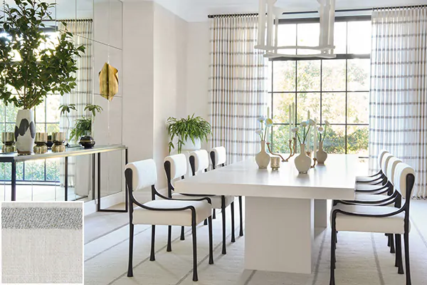 A modern dining room features Tailored Pleat Drapery made of Victoria Hagan's Lily in Silver for a subtle linear design