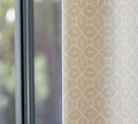 A close-up of Tailored Pleat Drapery made of Petal in Pearl has blackout lining which is often used for drapes vs curtains