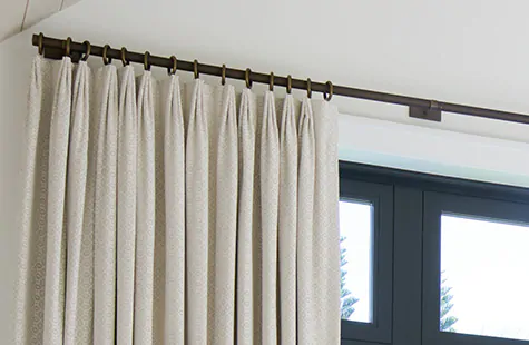 Tailored Pleat Drapery made of Victoria Hagan's Petal in Pearl hang luxuriously from a rod and rings hardware system