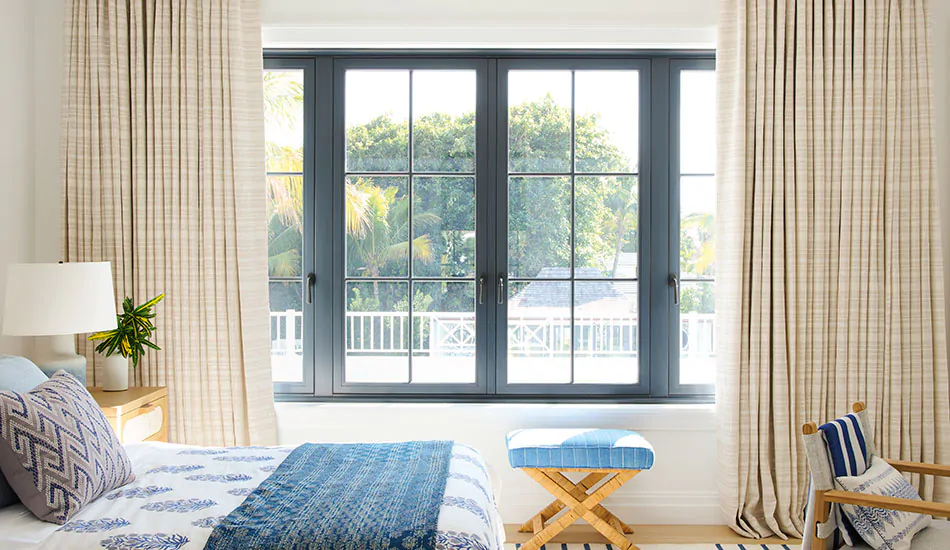 A bedroom with blue accents has curtains with a thick stack, showing how to hang curtains for a lush, full look