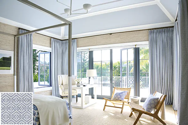 Colorful curtains made of Vanda in Sky complement the sandy wallpaper and crisp white trim of a coastal-inspired bedroom