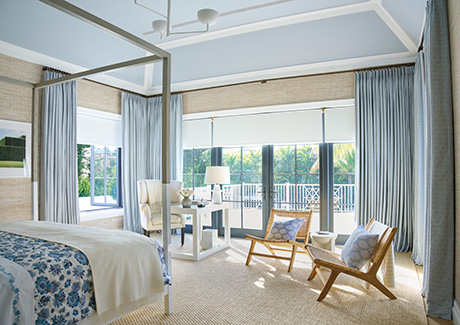Tailored Pleat Drapery made of Vanda in Sky matches the ceiling and contrasts the beige textured wallpaper in a large bedroom as elegant window coverings with added privacy