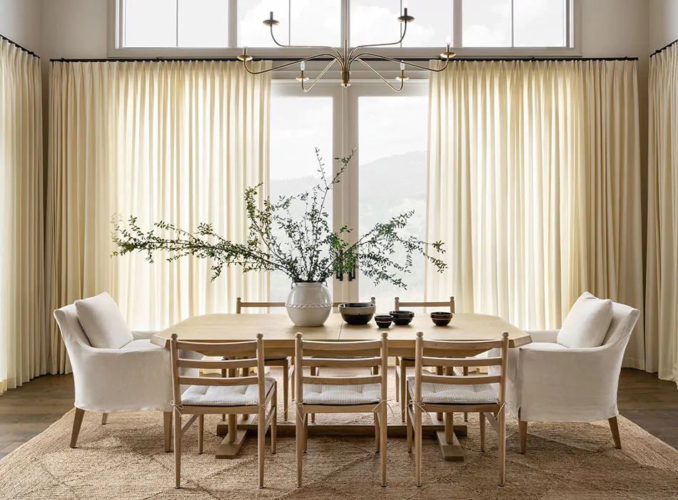 Tailored Pleat Drapery in Wool Blend Snow frames sliding glass doors in a high-end, modern dining room, offering a polished curtain idea for light control and privacy.