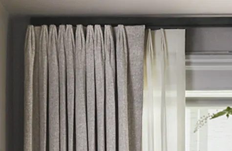 A double curtain rod features Tailored Pleat Drapery in Heathered Linen in Smoke and Wool Blend in Cloud