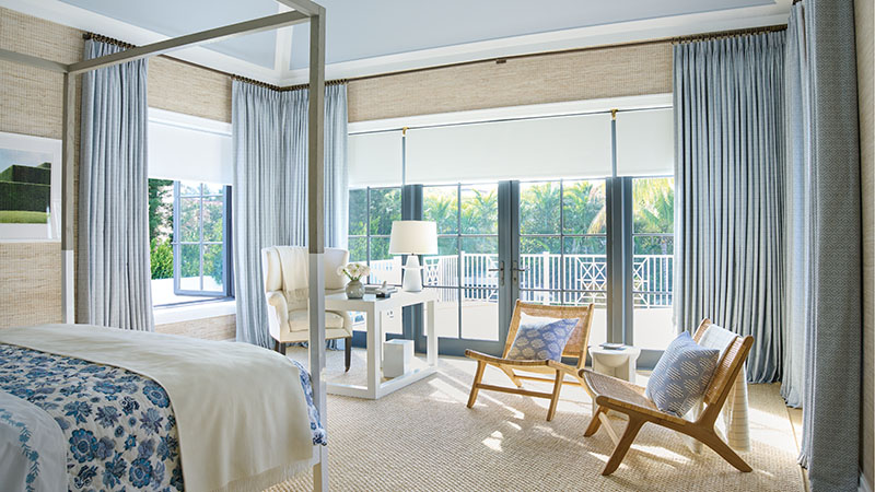 A large bedroom features coastal colors including Tailored Pleat Drapery in Vanda, Sky, and Roller Shades in Ava, Birchwood