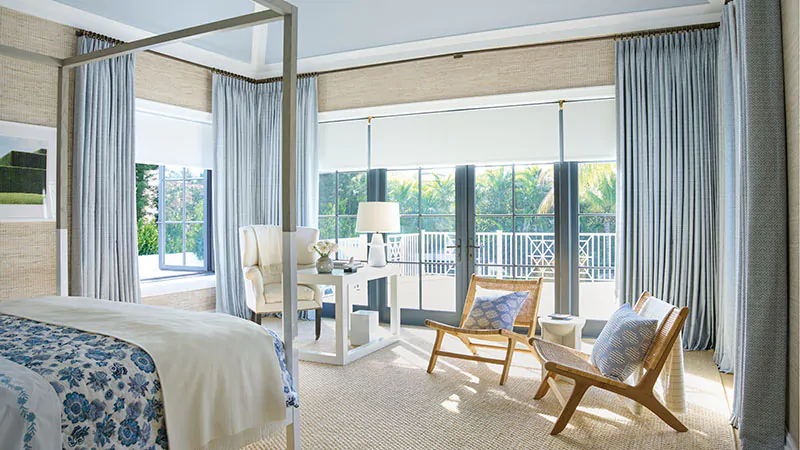 A large bedroom features coastal colors including Tailored Pleat Drapery in Vanda, Sky, and Roller Shades in Ava, Birchwood