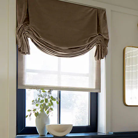 Tulip Roman Shades made of Velvet in Camel offer a luxe look to a room with warm white walls and gold decor