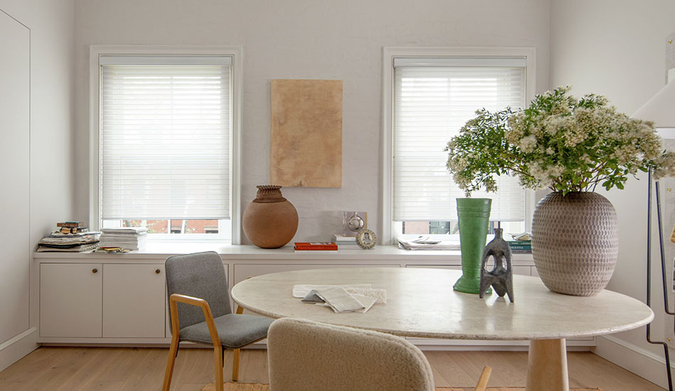 Types of blinds include Venetian Roller blinds made of Seaside in White in a creative workroom with a round table and flowers